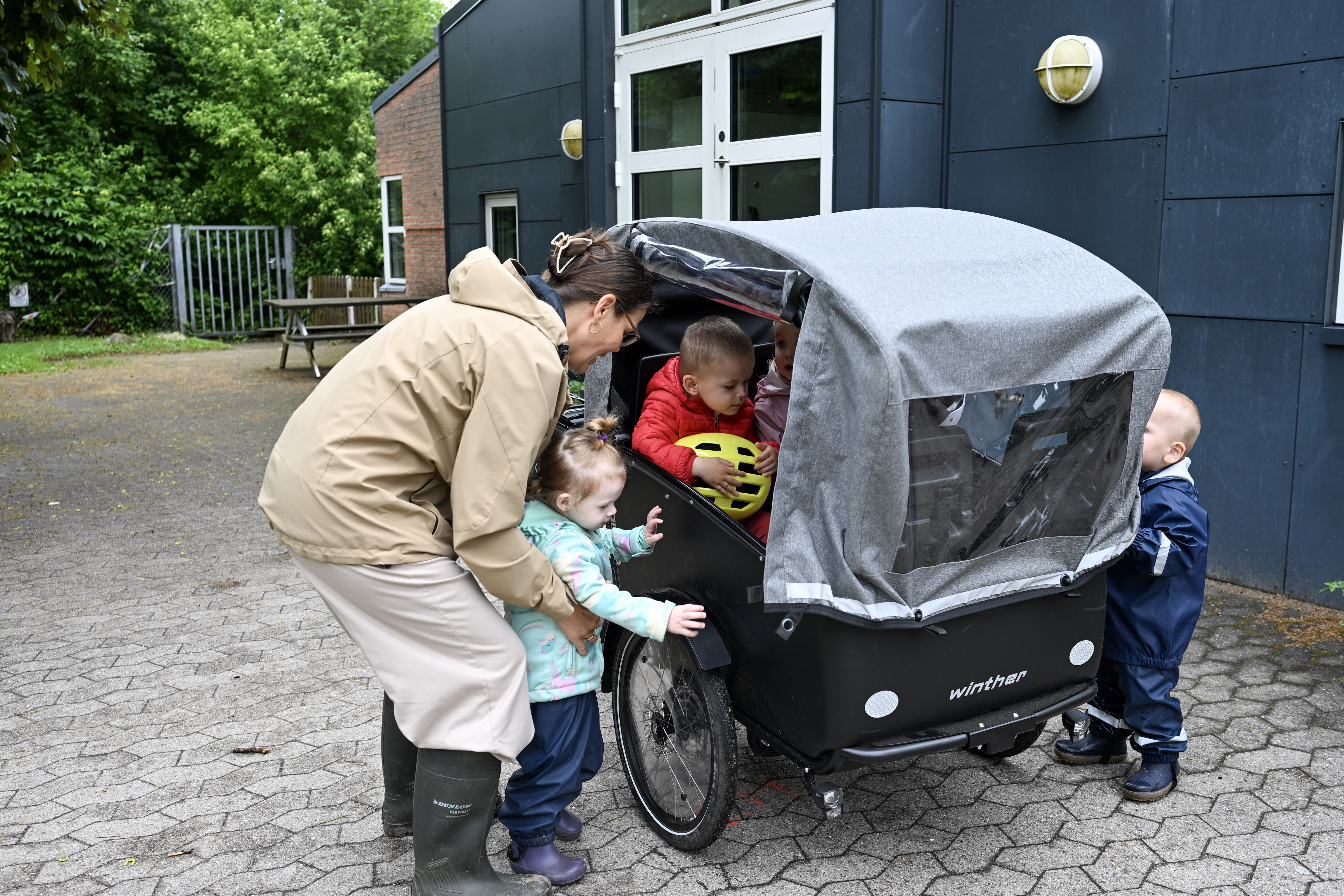 Voksen hjælper børn op i ladcykel